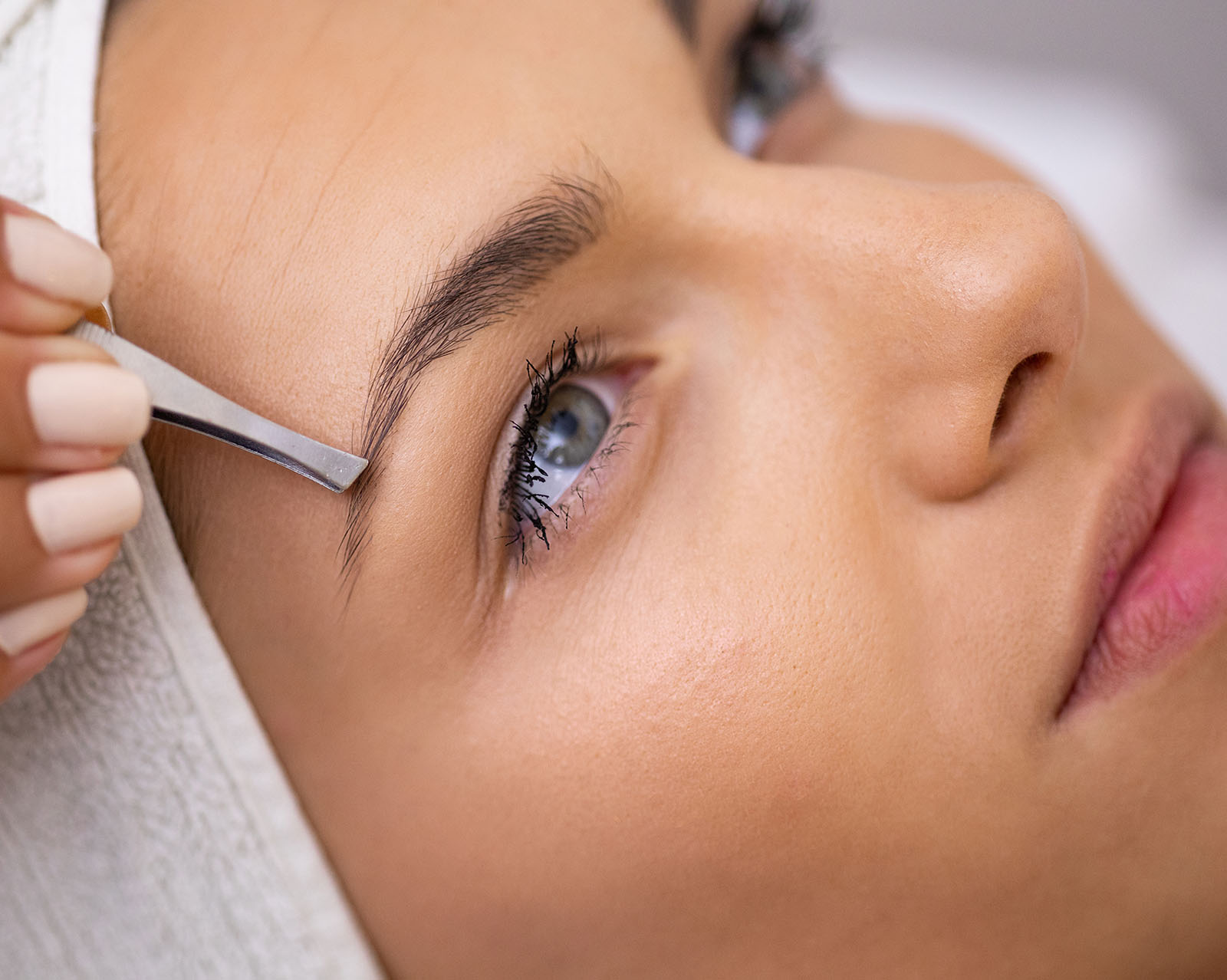 Augenbrauen zupfen Augenbrauen zupfen – Blick ins Gesicht einer jungen Frau der gerade die Augenbrauen gezupft werden, Friseur Salon Julia